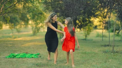 Mother and Daughter Laughing and Playing Together in a Sunny Park Afternoon