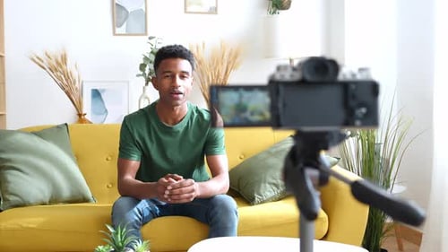 Young Man Vlogging Indoors, Sitting on Couch