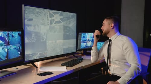 Security Officer Communicating on Walkie-Talkie in Control Room