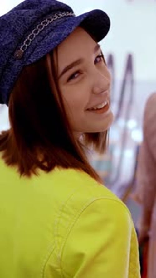 Woman in yellow jacket and blue hat smiles