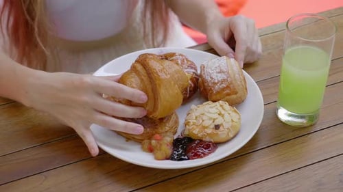 Closeup of Woman Eating Unhealthy Fresh Buns Sitting in Outdoors Cafe