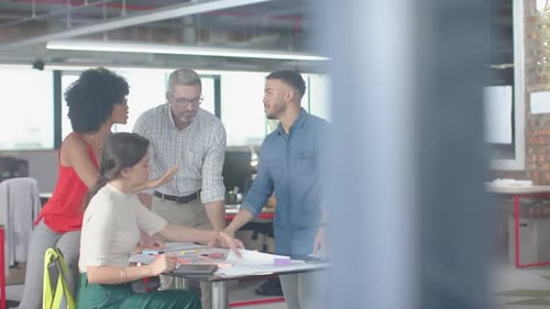 Team of diverse architects discussing over a plan at office