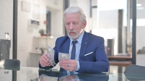 Old Businessman Counting Money in Office