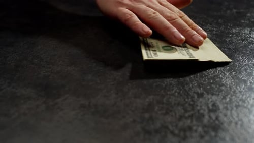 A Large Pile of Money is Lying on the Table Which is Being Stretched