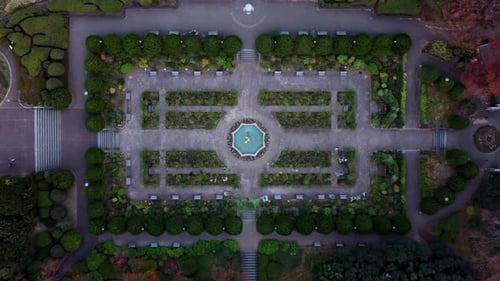 A symmetrically designed garden with central fountain at dusk, aerial view