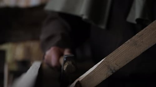 Master Craftsman Carves Wood with Adze, Splinters Falling in Rustic Workshop of Traditional Artistry