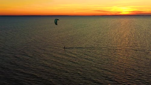 Aerial view. Kite surfing on the blue sea in the background of beautiful clouds. Sunset