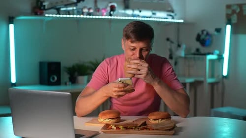 Young Adult Using Phone While Eating Burgers