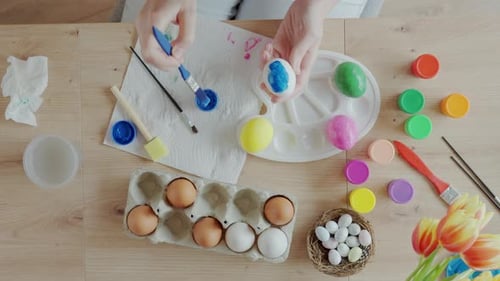 Woman Painting Easter Egg at Home with Pastel Paints