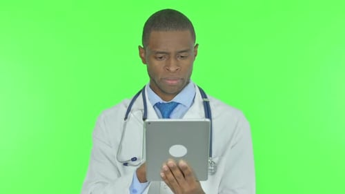 African Doctor using Digital Tablet on Green Background