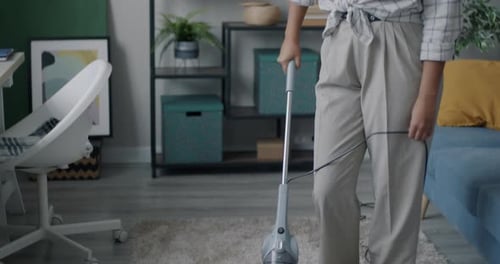 Woman Vacuuming Rug in Living Room Setting