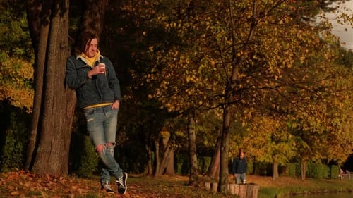 Young Adult Drinking Coffee in Autumn Park