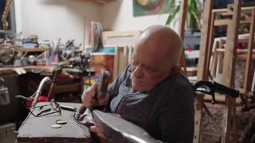 Senior Elderly Master Jeweler in Wheelchair Works in a Workshop