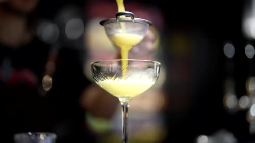 Barman Pouring Tasty Alcoholic Beverage Through Sieve to Crystal Glass Closeup View in Bar