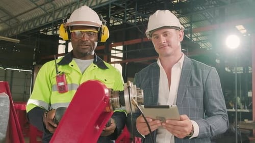 An engineer demonstrates robotic arm control to customer in industry factory.