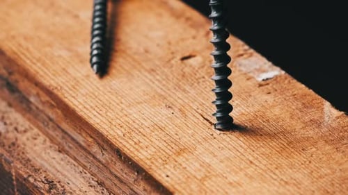 Closeup of a Screw Being Driven Into a Block of Wood with a Screwdriver