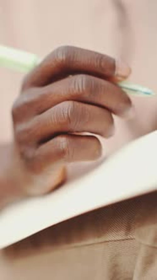 Close-up of young student's hand taking notes
