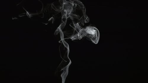 Wispy smoke rising against a black background in studio
