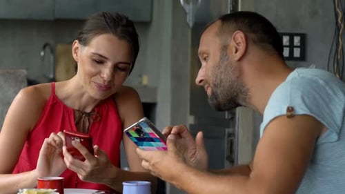 Man and Woman Using Phones at the Table