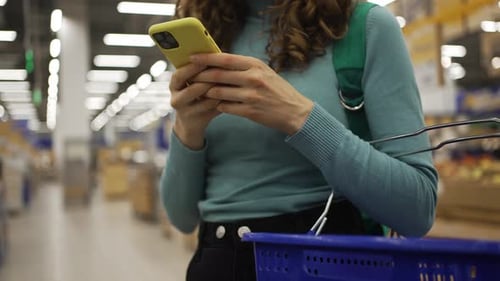 Woman Using Smartphone While Shopping in Supermarket