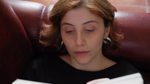 Woman Reading Book on Couch Indoors