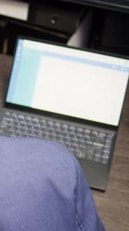 Adult Typing at Desk With Binder and Laptop