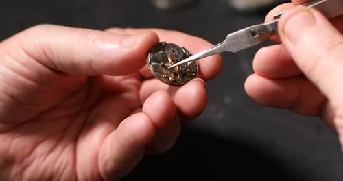 Watchmaker Repairing Watch Mechanism with Tweezers Close Up