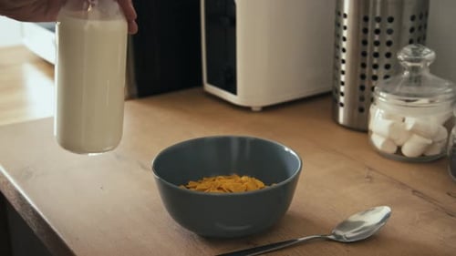 Pouring Milk on Breakfast Cereal in Kitchen