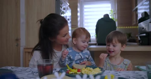 Woman and Children Eating Breakfast at Table in Kitchen
