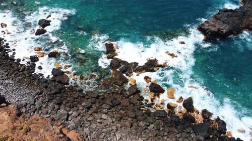 Cinematic Drone View of Deep Blue Sea Topdown Scenery with White Foamy Waves Stone Rocks Coastline