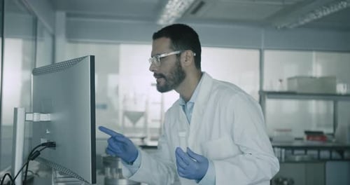 Scientist in Lab Coat Analyzing Data on Computer