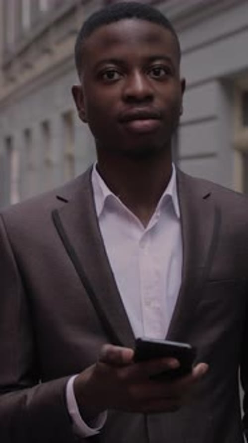 African Man in Suit Standing on Street with Smartphone