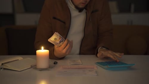 Man Counting Money by Candlelight at Night