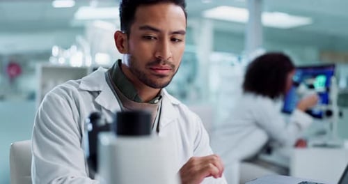 Man Using Microscope in Brightly Lit Laboratory