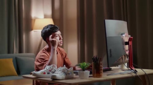 Asian Boy Footwear Designer Thinking While Working On A Desktop Computer At Home