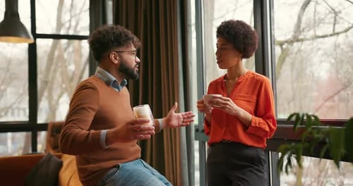 Man and Woman Talking and Drinking Coffee Indoors