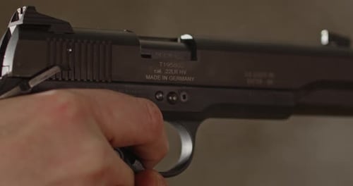 Extreme close up of pistol being aimed with a man's finger on the trigger