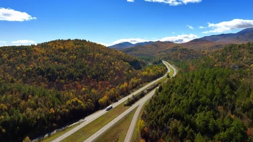 Lorries ride by the highways in the mountainous area on sunny day.