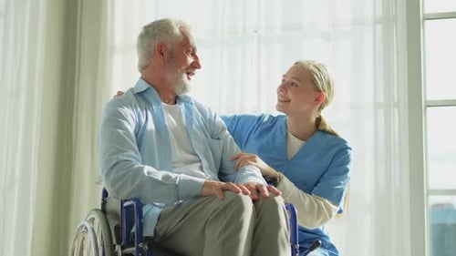 Smiling Senior Man in Wheelchair with Caregiver