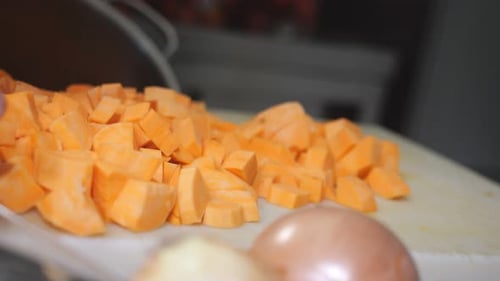 African chef preparing concassé cut yam and sweet potato on cutting board during traditional cooking