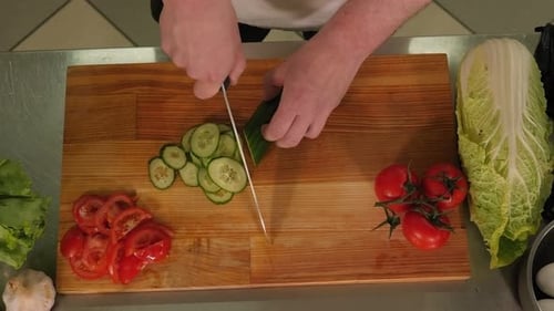 Closeup of a Professional Chef Slicing a Fresh Cucumber on a Cutting Board
