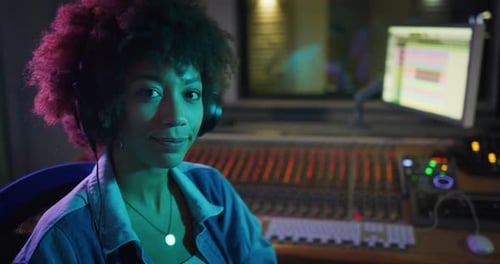 An young happy professional african female sound producer is taking off headphones while recording