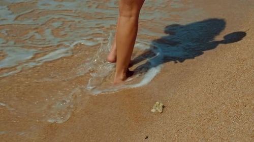 A Woman is Wading in the Water at the Beach Barefoot