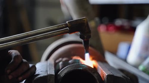 Metalwork in Progress A Torch Flame is Applied to a Cylindrical Metal Object Held in Vise The Flame