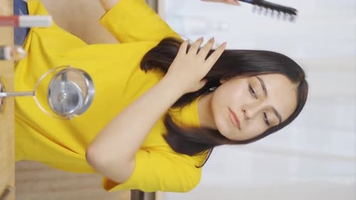 Vertical video of Young woman combing her hair. Hair care.