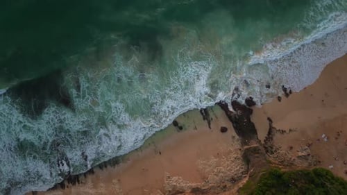 waves of the indian ocean crashing on the beach in uluwatu, bali at sunset