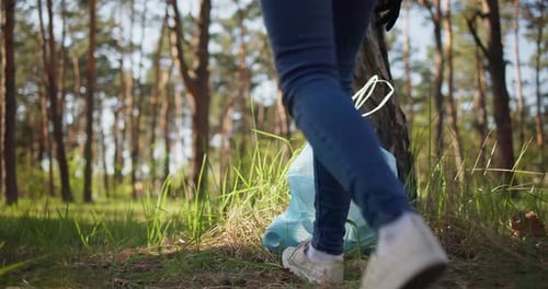Una mujer se lleva una bolsa de plástico con basura recogida en el bosque