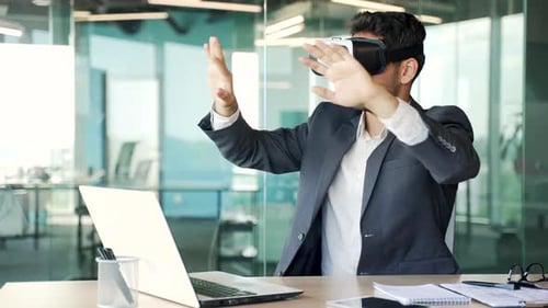 Young businessman works using VR glasses in virtual reality simulator sitting at workplace