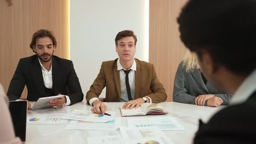 Business People Meeting Around Conference Table Discussing Charts