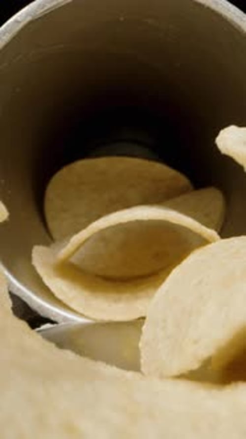 Vertical video. Saddle-shaped chips neatly arranged on the table, the camera zooms into their can.
